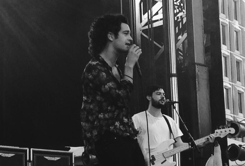 Lead singer of The 1975 Matty Healy next to Ross MacDonald on bass in “The City”.