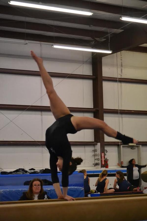        Junior Victoria Derousi does a back walk-over on the beam for NK’S gymnastic team.   
