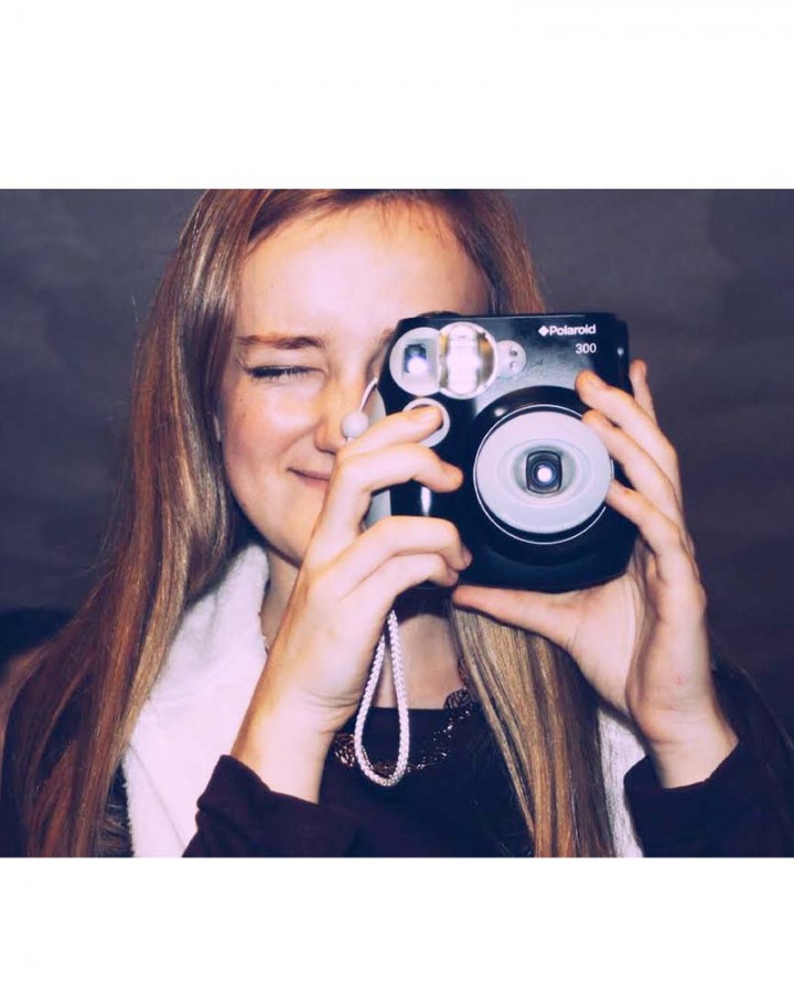 Senior Emily Schott takes a photo with a Instax camera.