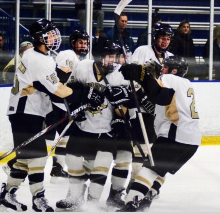 Junior Sean Stamp is crowded by his teammates afar scoring a goal.