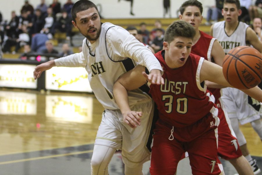 Seniors Mike Ferrie, left, and Thor Brochu, back right, fight for the ball during their game against Cranston High School-West on Dec. 16. North Kingstown won the game, 68-48.